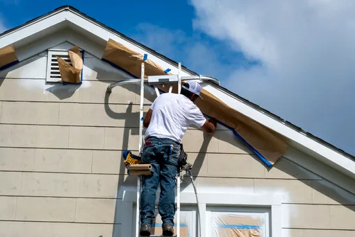 Painter masking windows and vents on a Burbank Hills home before painting